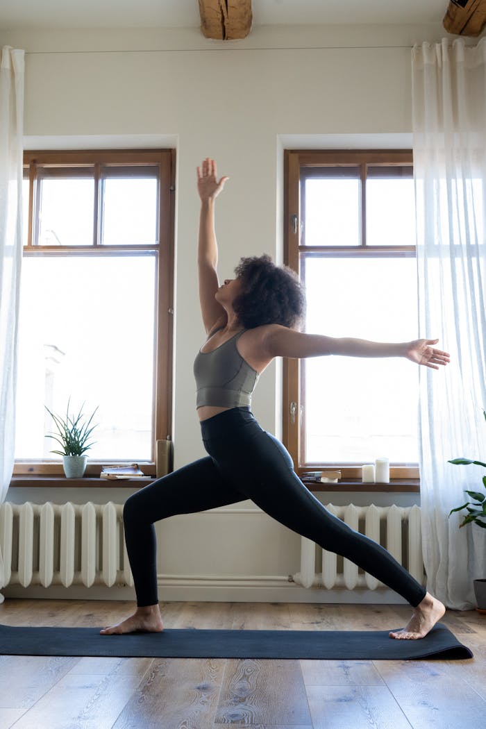 Woman practicing yoga in a well-lit modern home setting, promoting wellness and tranquility.
